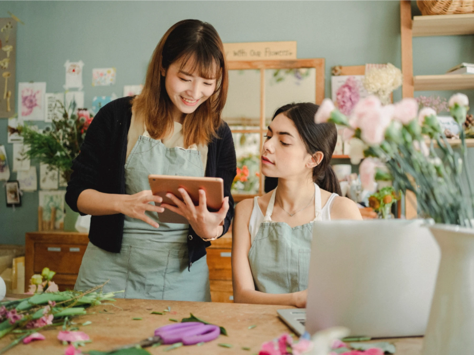 Positive women with gadgets in floral shop